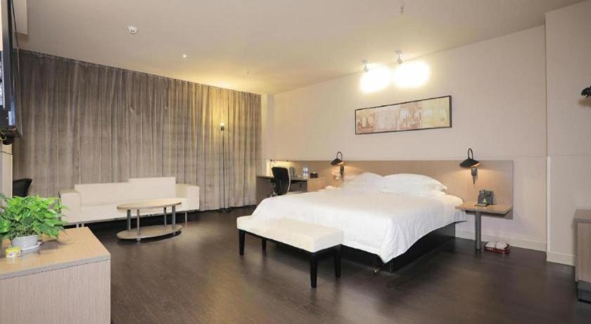 ein Schlafzimmer mit einem großen weißen Bett und einem Tisch in der Unterkunft Jinjiang Inn Select Urumqi Midong Avenue in Miquan