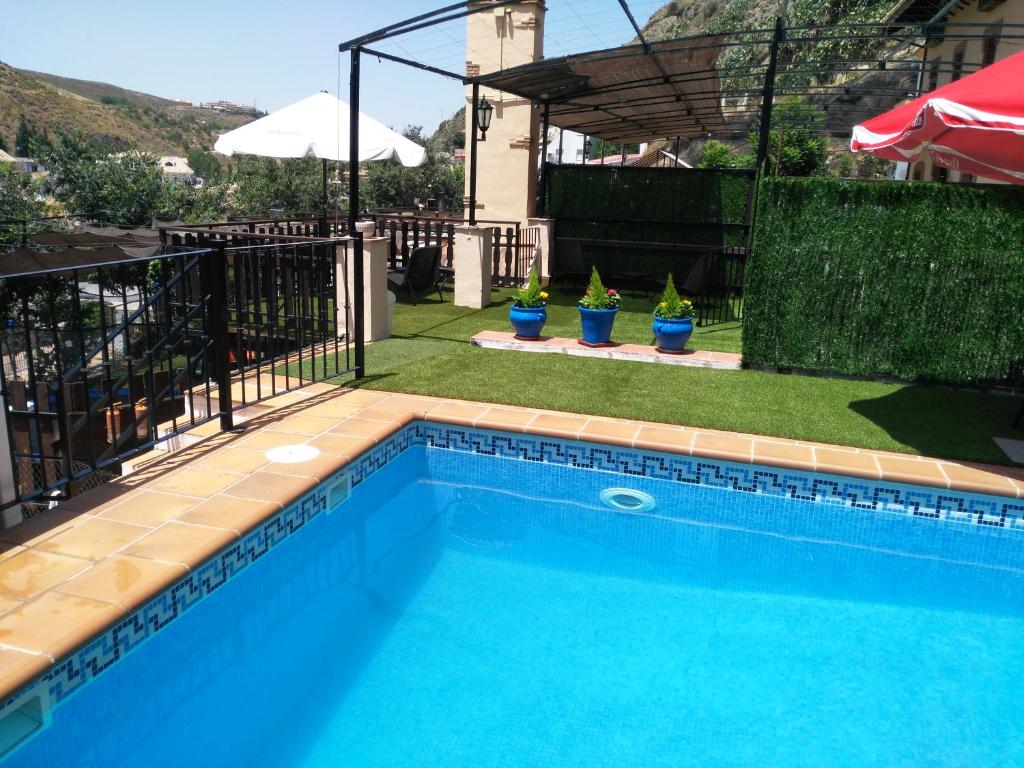 una piscina de agua azul en un patio en Hotel Rural Huerta del Laurel, en Monachil