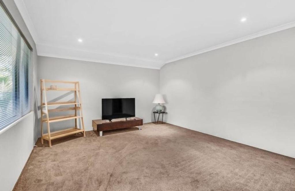 an empty living room with a tv and a ladder at Room in a house in Eaton