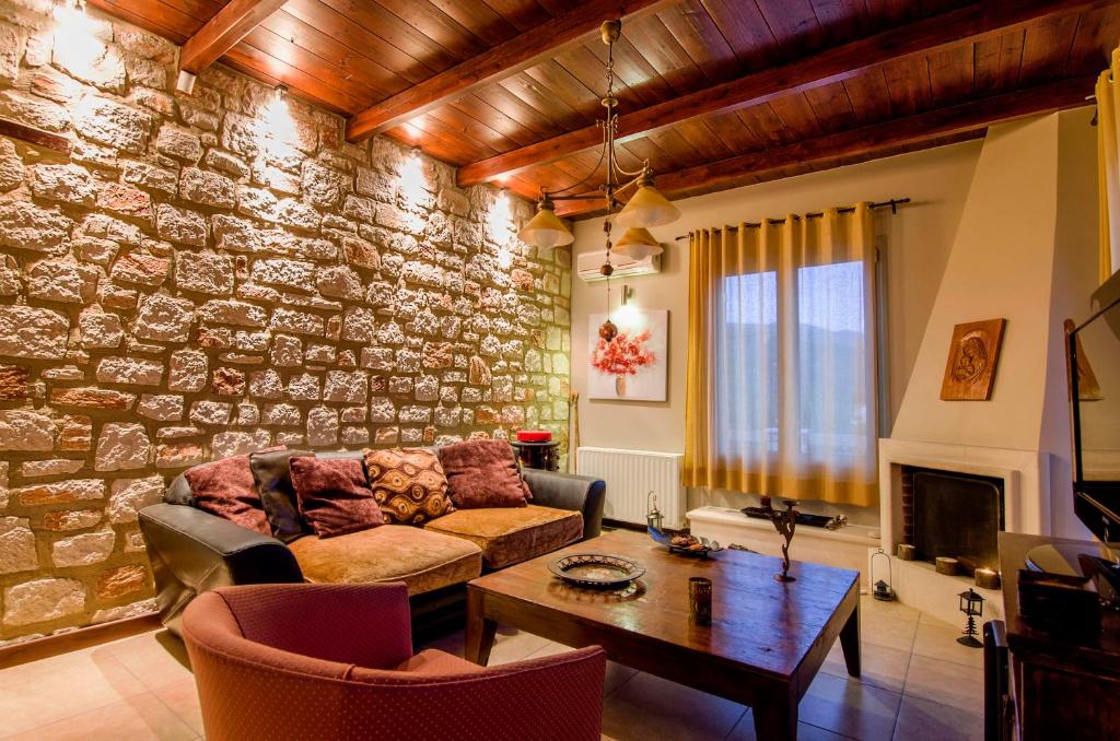 a living room with a stone wall with a couch and a table at Memories villa in Zakynthos
