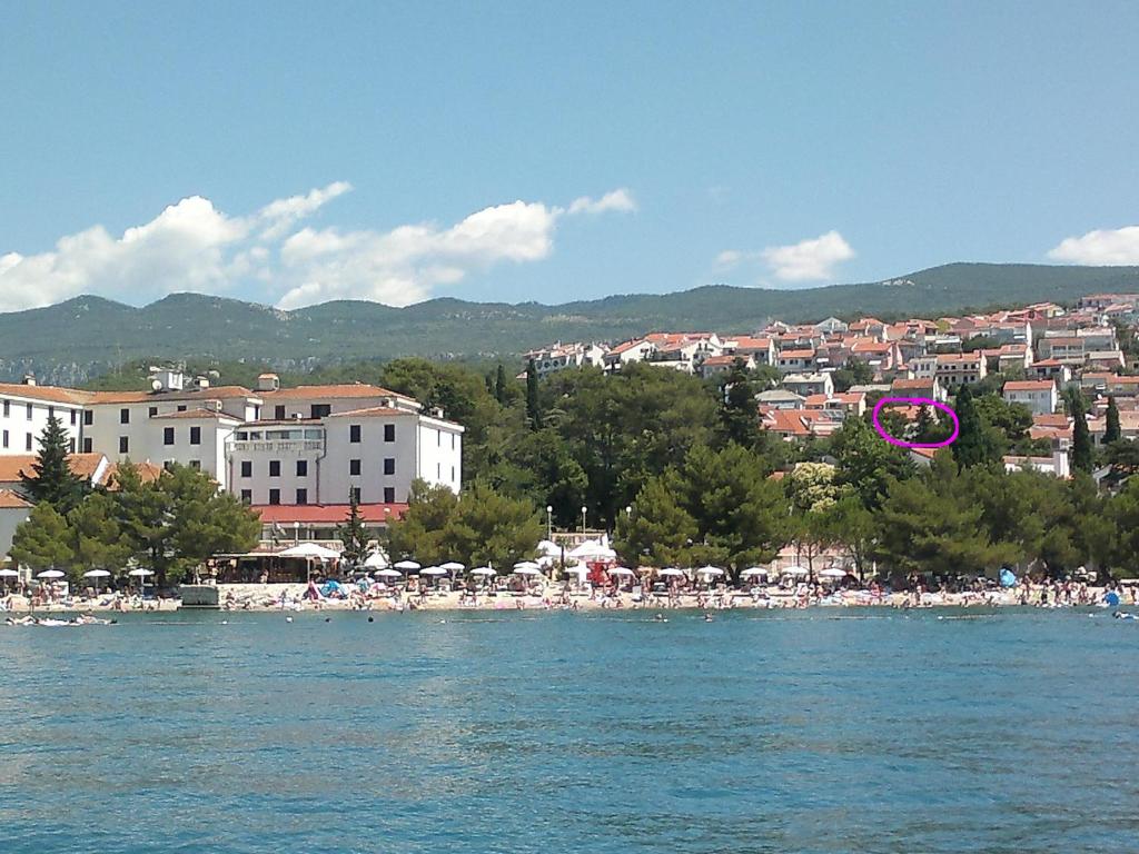 a beach with a group of umbrellas and people on the water at Loredana Apartments in Crikvenica