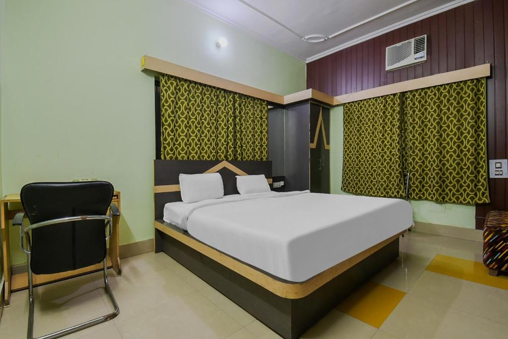 a bedroom with a large bed and a chair at Hotel O Chandralok by CLOVETREE in Muzaffarpur