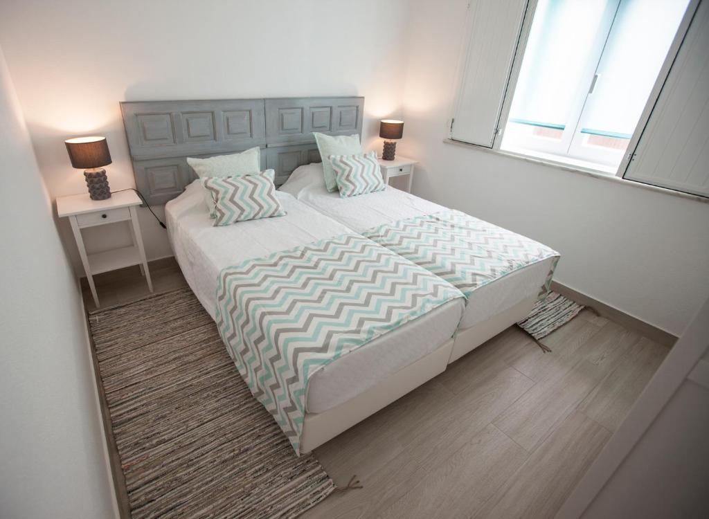 Un dormitorio con una cama grande con dos mesitas de noche. en Casas Burnay I, en Ericeira