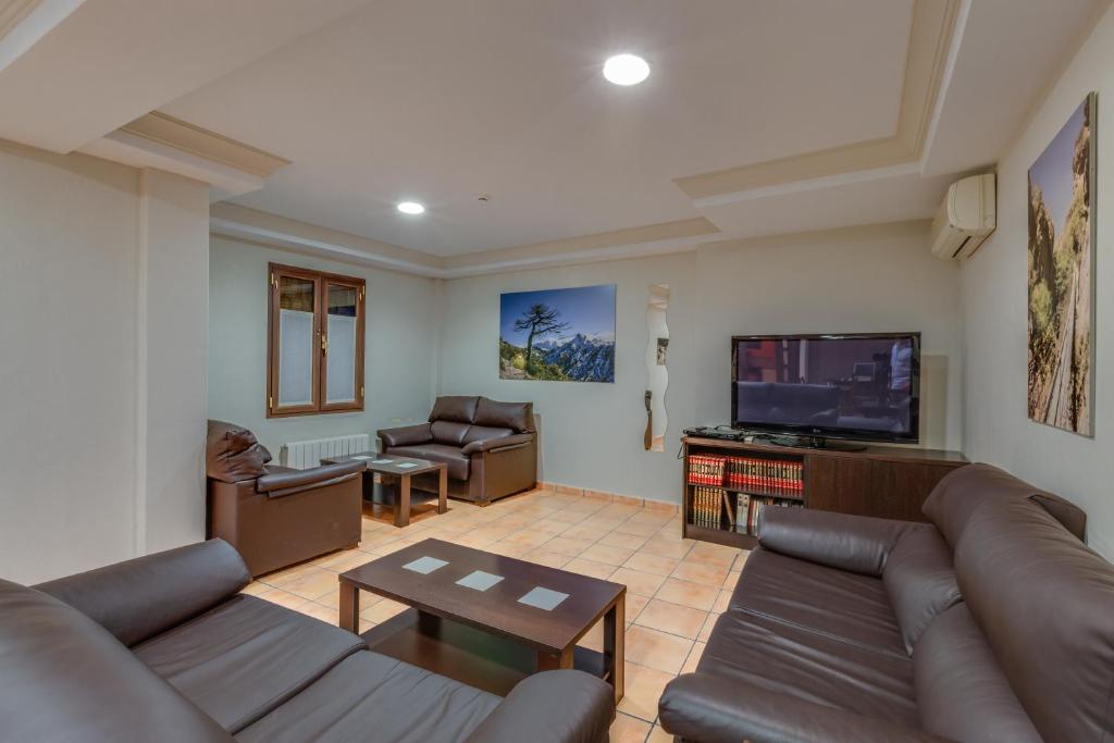 sala de estar con sofás y TV de pantalla plana. en Hotel Rural Huerta del Laurel, en Monachil