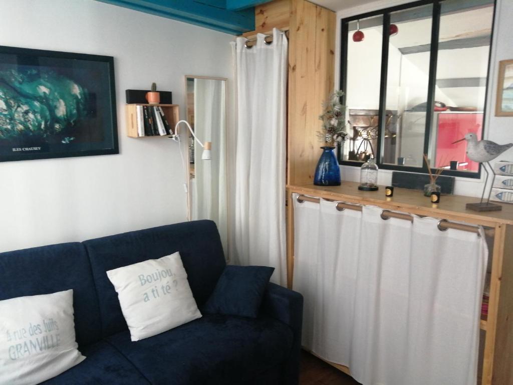 Una sala de estar con un sofá azul y una ventana. en Cryste Marine, en Granville