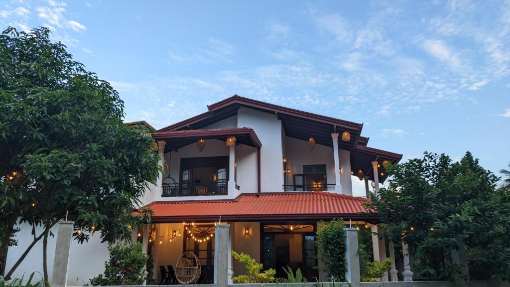 une grande maison blanche avec un toit rouge dans l'établissement Lake side haven villa, à Tangalle