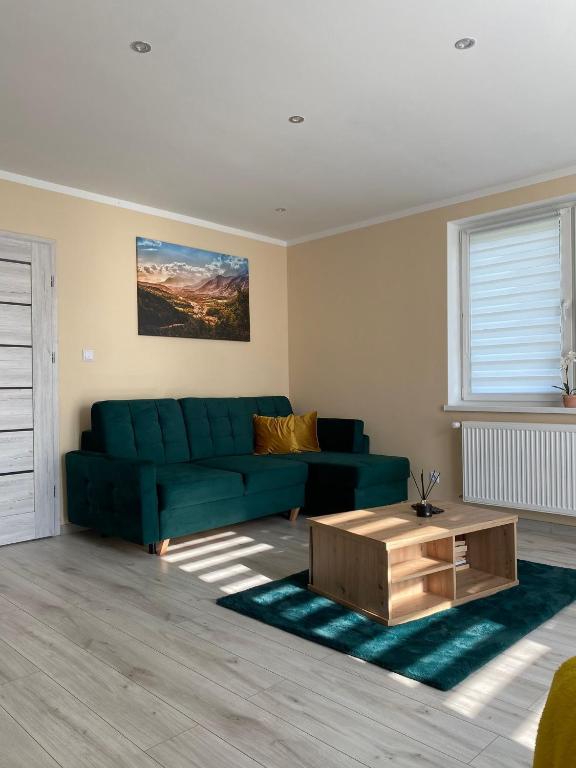 a living room with a green couch and a coffee table at Apartament Koszarawa in Koszarawa