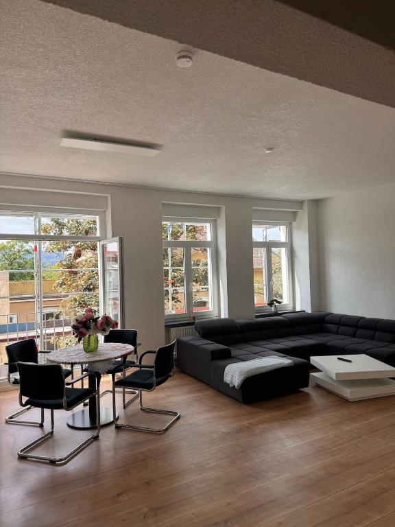 a living room with a black couch and a table at 2 Bedroom Apartment at Grenzach train station in Grenzach-Wyhlen