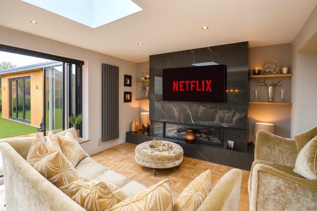 a living room with a couch and a tv at Elegant and Spacious 4 Bedroom Property with Driveway Parking in Sutton