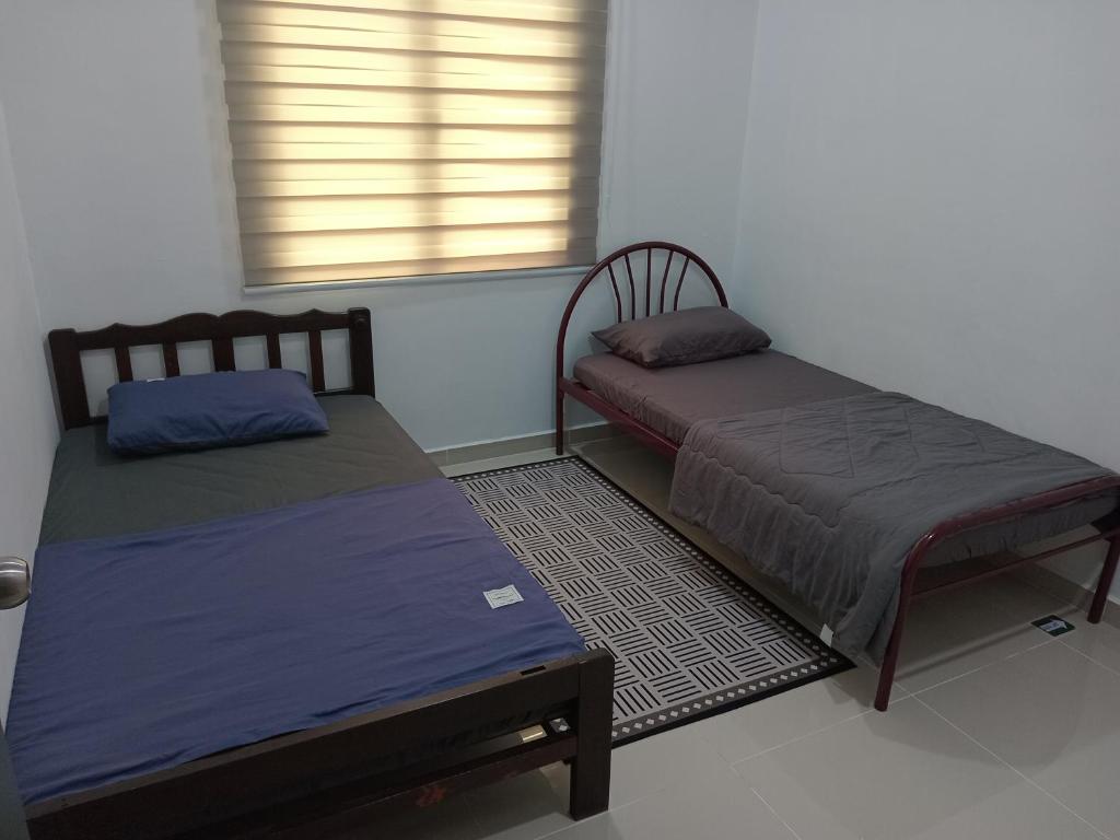 due letti singoli in una stanza con finestra di K&A Family Homestay a Kuala Terengganu