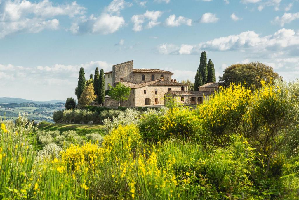 a house on a hill with a field of flowers at Castello La Leccia in Castellina in Chianti