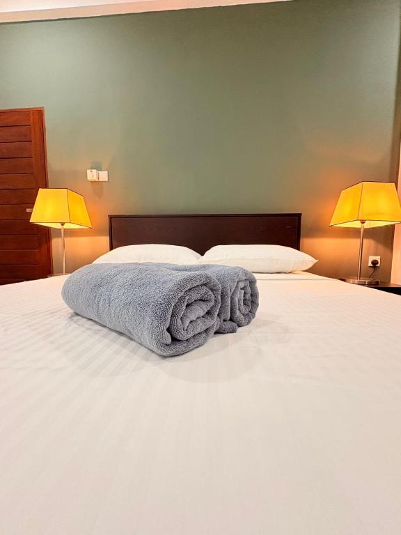 a blue towel laying on a bed with two lamps at Motel K in Ambalangoda