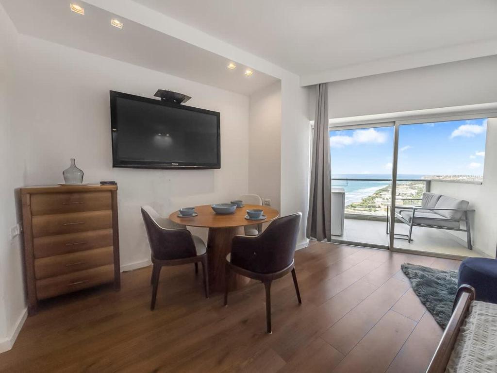a living room with a table and chairs and a television at The Sharon Sunset Loft in Herzliya B