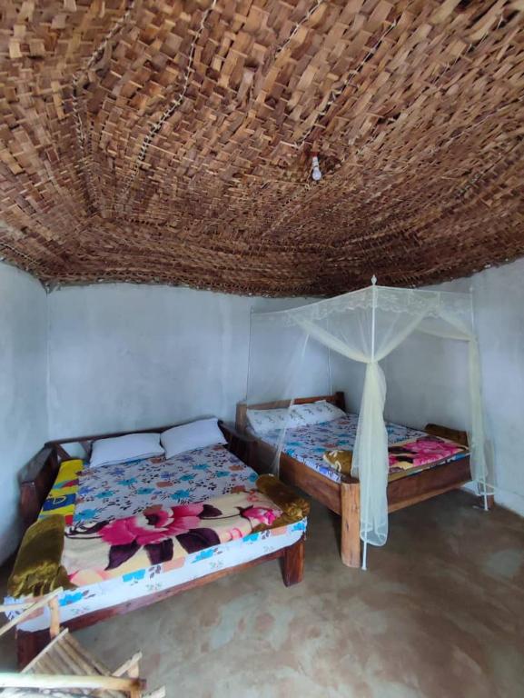 two beds in a room with a straw roof at Sipi Backpackers in Kapchorwa