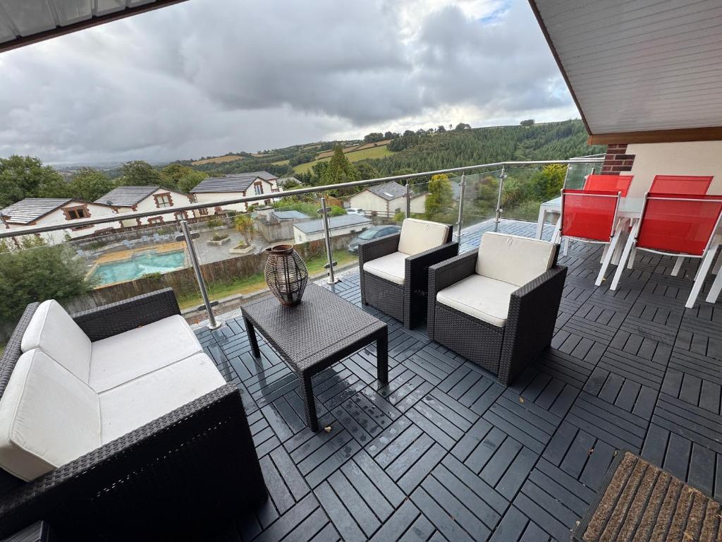 a balcony with chairs and a table and a pool at Between the Moors Hideaway in High Bickington