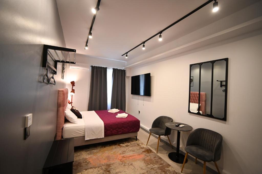 アテネにあるAphrodite Suite Klathmonos by Zeus Suitesのベッドとテーブルと椅子のあるホテルの部屋