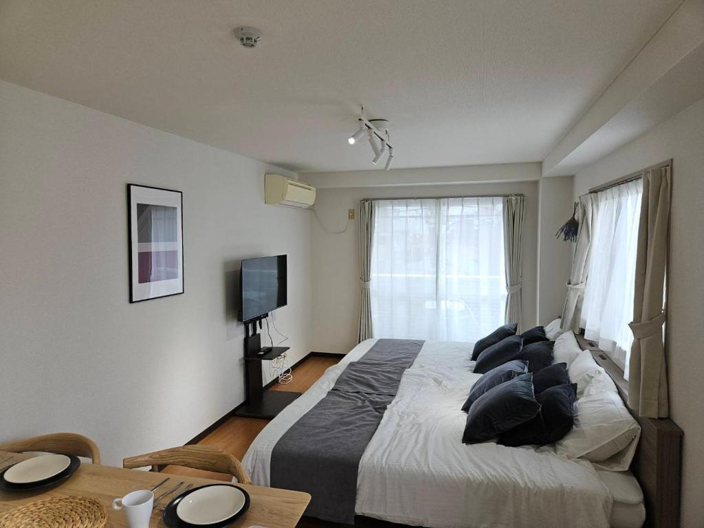 a bedroom with a bed and a table and a television at ホテルレスポワール402 in Tokyo