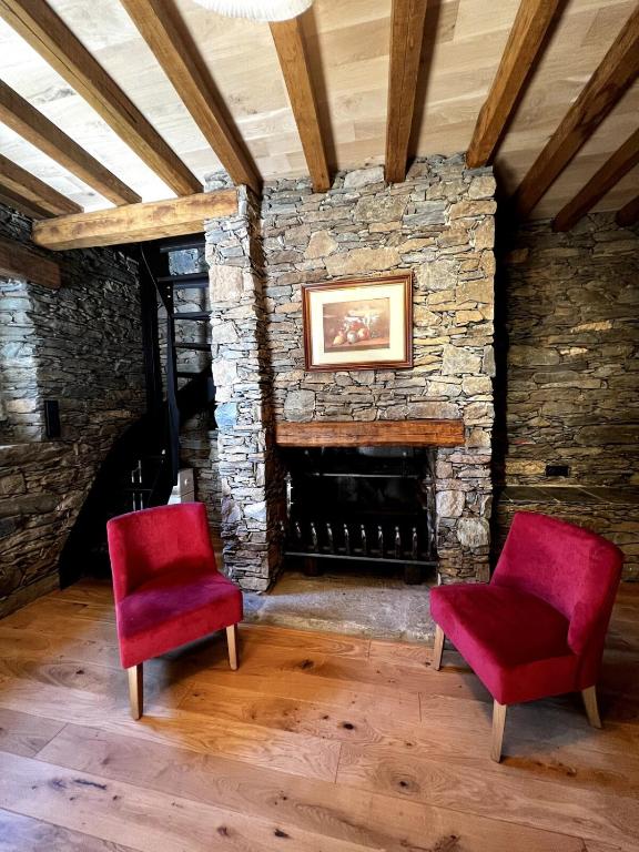 two red chairs in a room with a stone fireplace at Bergerie in Volpajola