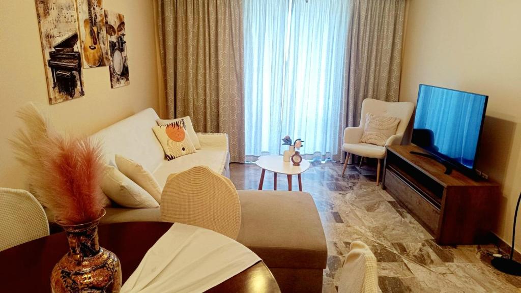 a living room with a couch and a tv and a table at AnyfApartment Kalamata in Kalamata