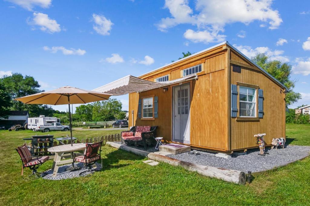 una casetta minuscola con un tavolo e un ombrello di Cozy Tiny Home Retreat on Shenandoah Valley Farm cabin a Mount Jackson