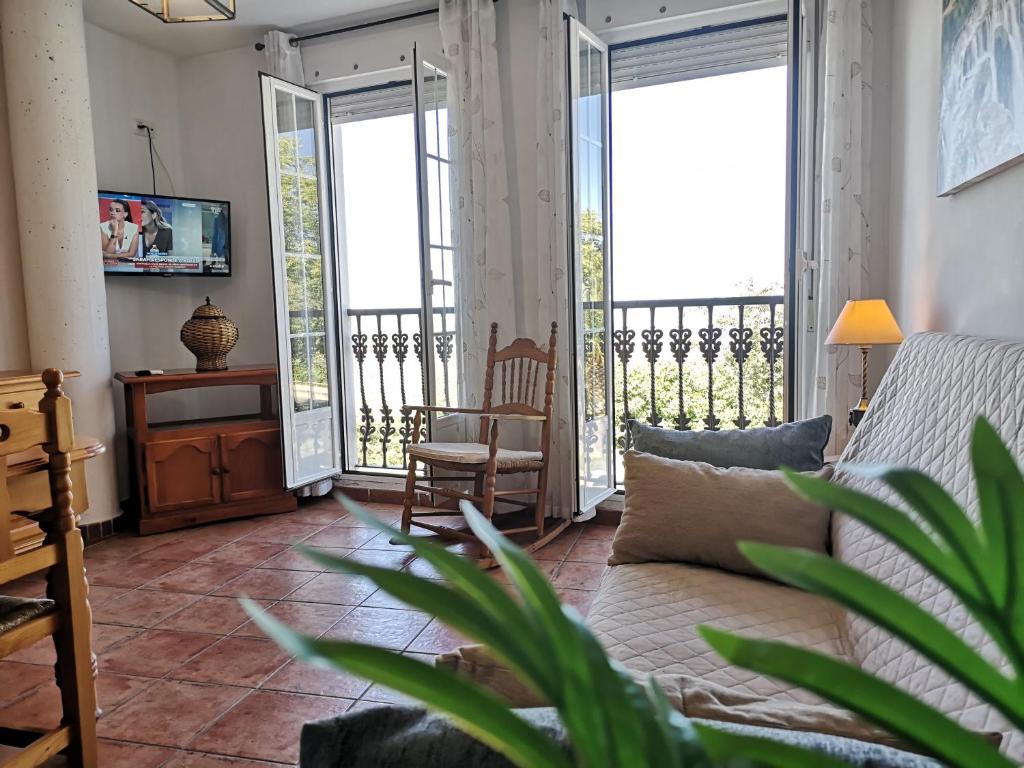a living room with a couch and large windows at Mirador de la Campiña in Cazorla