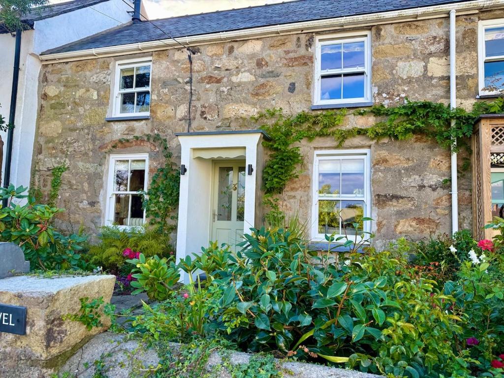 an old stone house with flowers in front of it at Arwel Cottage 3 bedroom in Llanbedrog