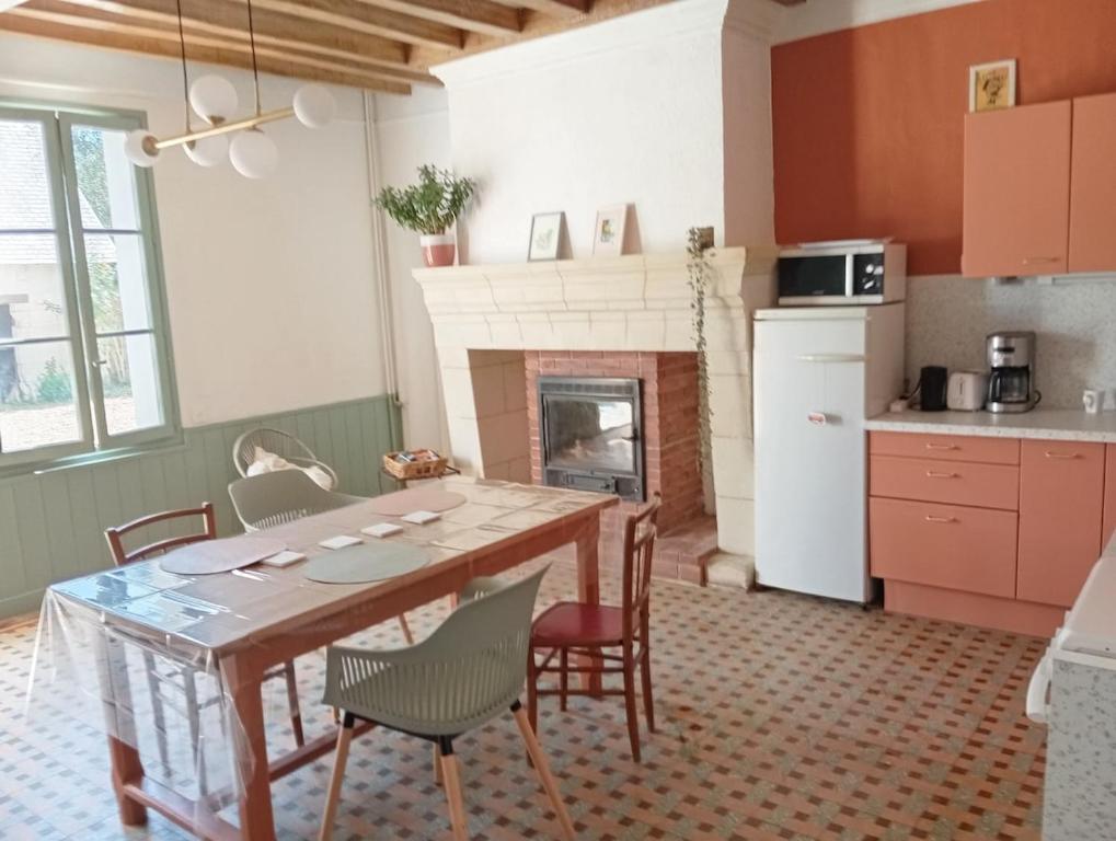 a kitchen with a table and chairs and a fireplace at Gîte 3 chambres dans Longère aux Rosiers-sur-Loire in Le Thoureil