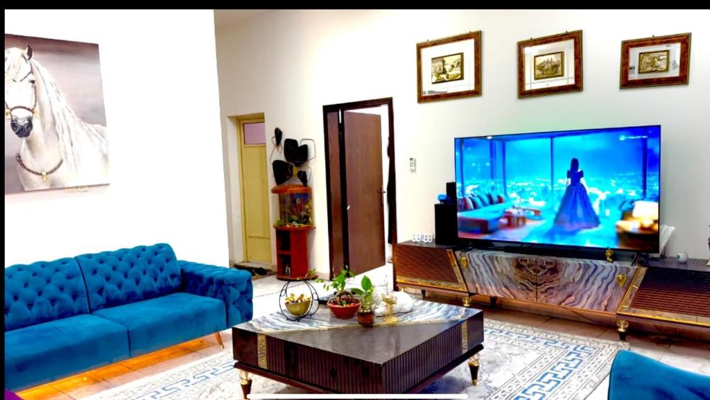 a living room with a blue couch and a large tv at Al Jouri in Dammam