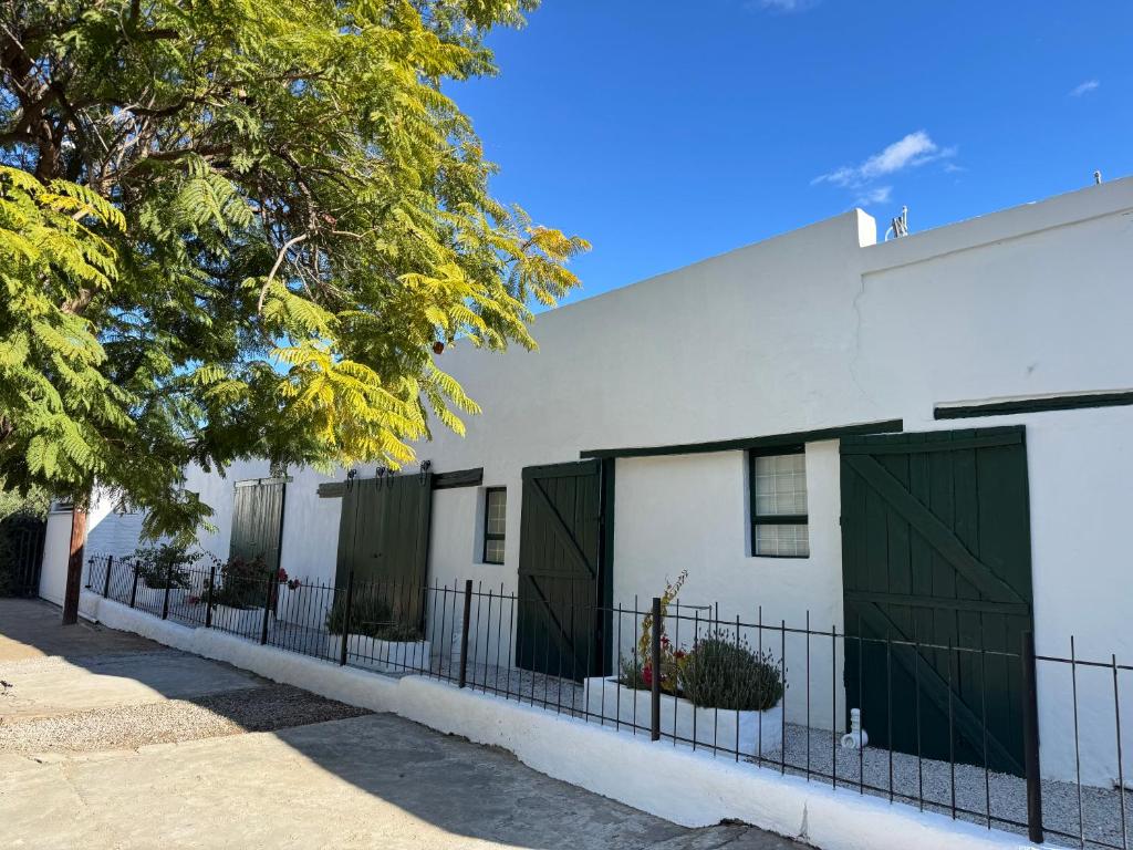 a white building with green doors and a fence at Rietjiesbos in Graaff-Reinet