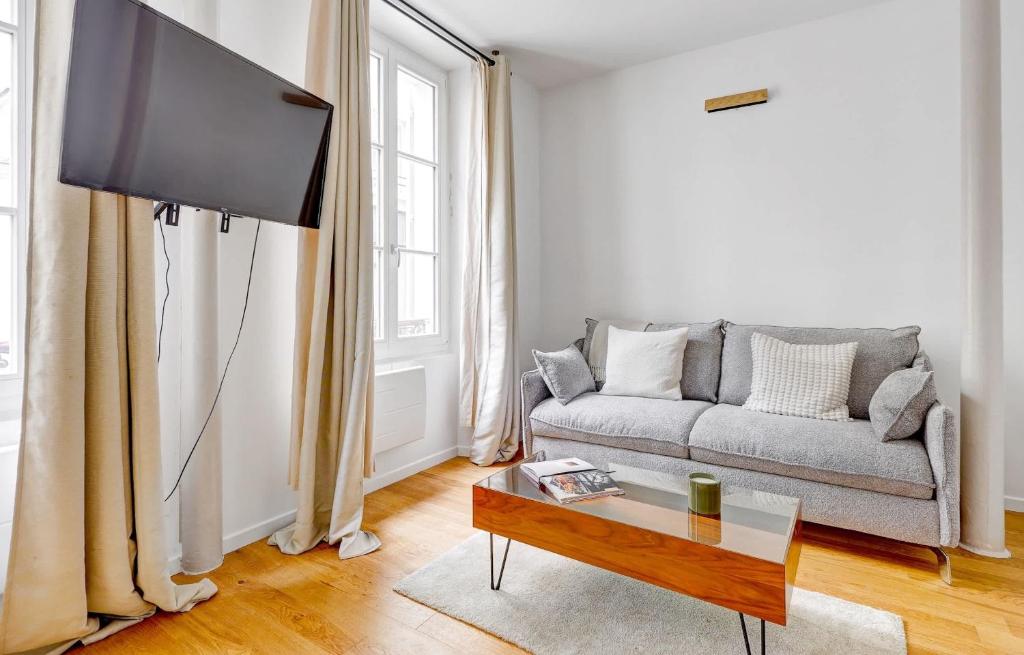 a living room with a couch and a flat screen tv at BnBNova - 1BR - Eiffel Tower & Rue Gros Caillou in Paris