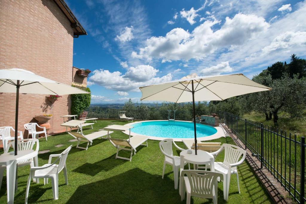 eine Terrasse mit einem Pool, Stühlen und einem Sonnenschirm in der Unterkunft Casa Lari in San Gimignano