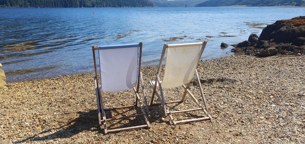 twee stoelen op een strand naast het water bij Carrick Chalets -2 in Carrick