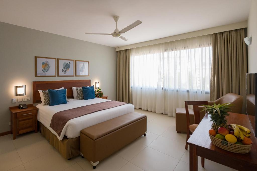 a hotel room with a bed and a table with fruit on it at Sea Cliff Court Hotel & Luxury Apartments in Dar es Salaam