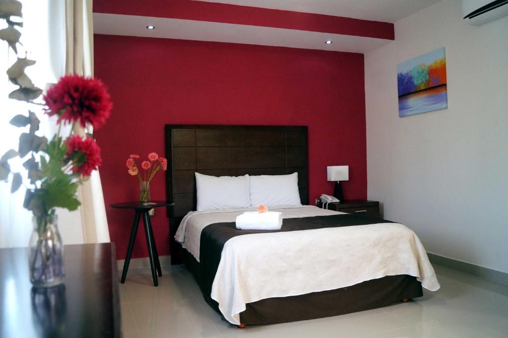a bedroom with a bed with a red wall at Hotel Casa Palomino in Mérida