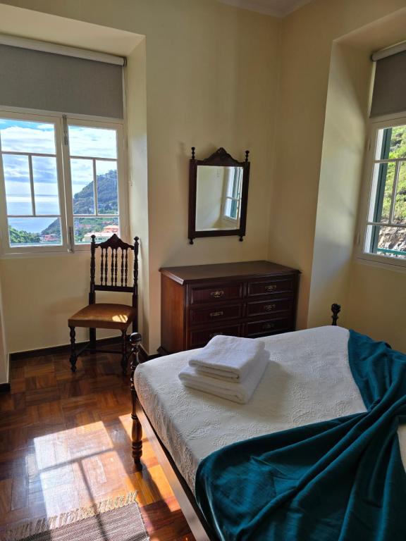 een slaapkamer met een bed, een spiegel en een stoel bij Banana Lovers - Banana Farm in Ribeira Brava