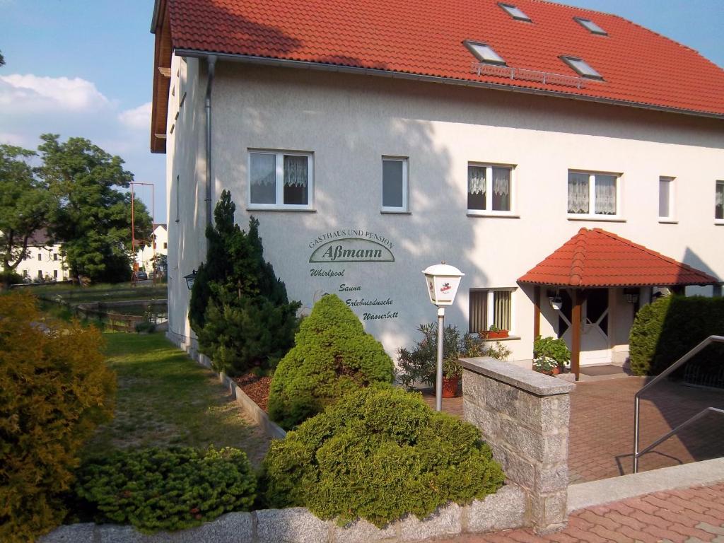 Hotel & Pension Aßmann في Hochkirch: مبنى ابيض كبير بسقف احمر