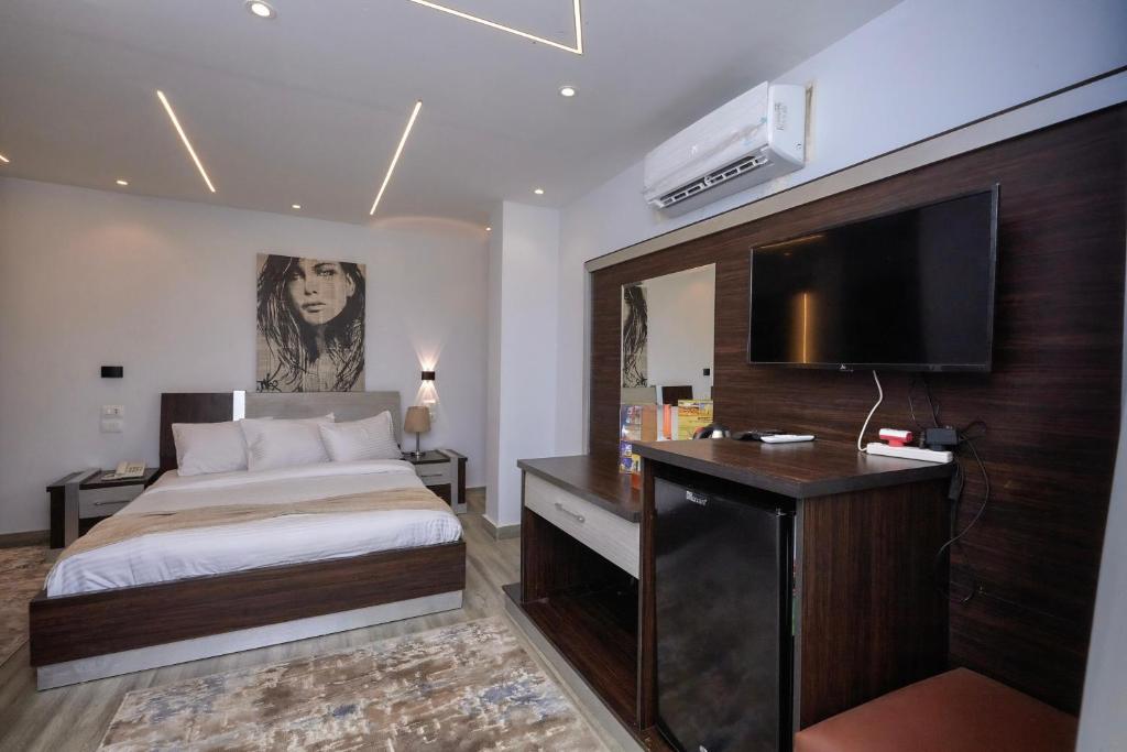 a bedroom with a bed and a desk with a television at Kayan Pyramids View in Cairo