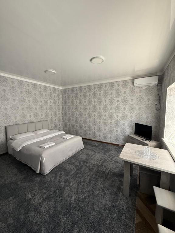 a bedroom with a large bed and a desk at Kubat Guest House in Tokmok