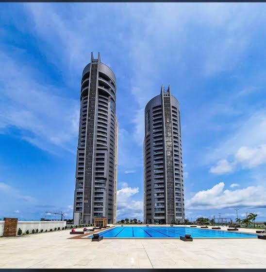 two tall buildings next to a swimming pool at 3 Bedroom Luxury Apartment in Eko Atlantic City in Lagos