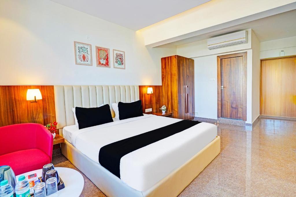 ニューデリーにあるHotel IVYのベッドルーム1室(大型ベッド1台、赤い椅子付)