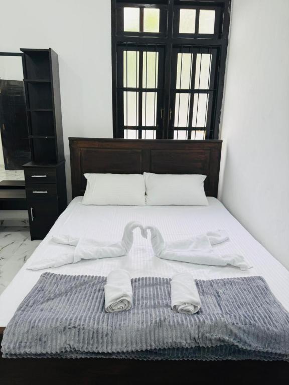 a bed with two white towels on top of it at DP Aejis in Dehiwala
