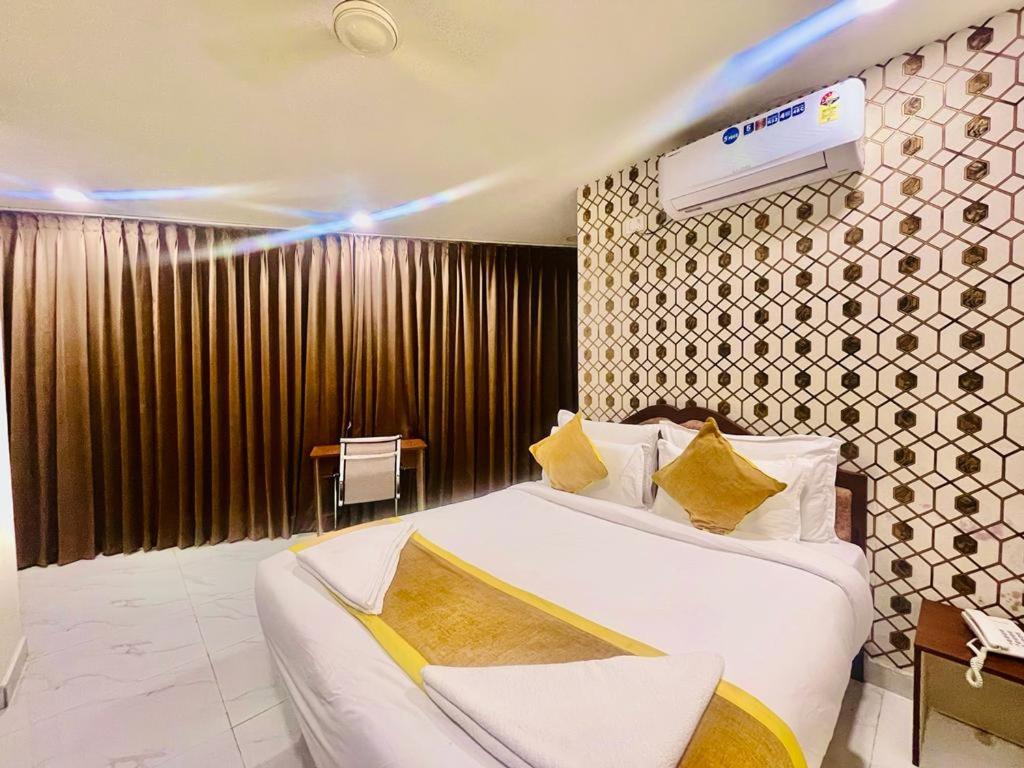 a bedroom with a large white bed with yellow pillows at Hotel Eagle Grand Airport Zone in Shamshabad