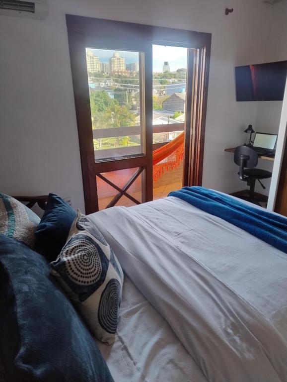 a bedroom with a bed and a window with a view at Sobrado 4 km do Shopping Iguatemi, Parque Germânia e Hosp Conceição in Porto Alegre
