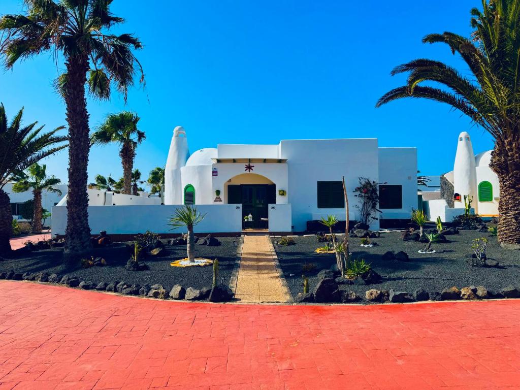 ein weißes Gebäude mit Palmen davor in der Unterkunft Villa Karisa in Playa Blanca