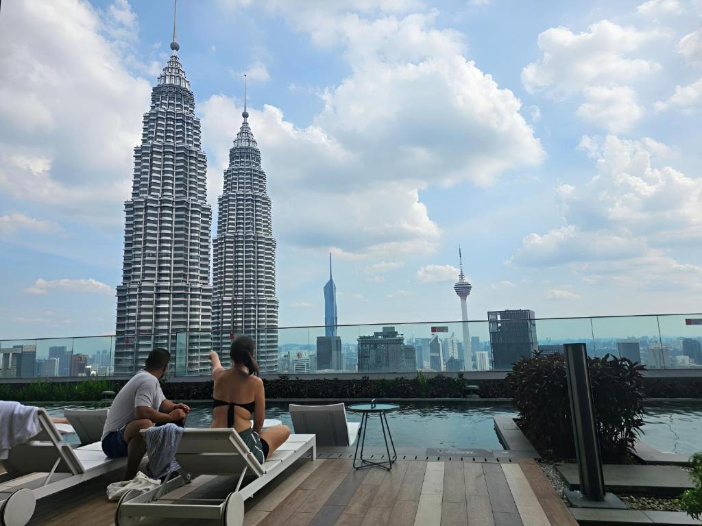 a man and a woman sitting on a rooftop with the petronas towers at Premier Suites Twin Towers at Star Residences in Kuala Lumpur