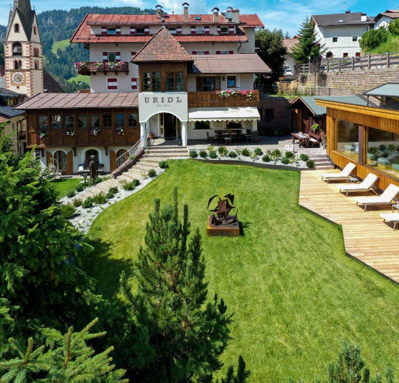 a person sitting on a bench in the yard of a house at Charme Hotel Uridl in Santa Cristina Gherdëina