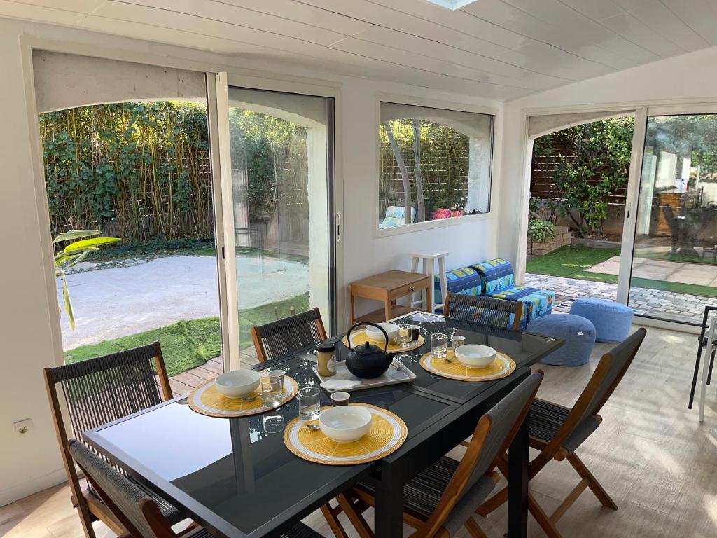 Un comedor con mesa y sillas y ventanas. en Évasion méditerranéenne bas de villa Cath, jardin privé, parking, en Sanary-sur-Mer