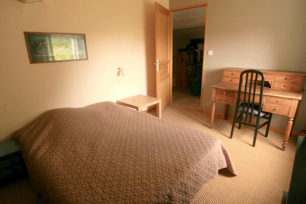une chambre avec un lit, un bureau et une chaise dans l'établissement le calme à la campagne, à La Celle-sous-Gouzon