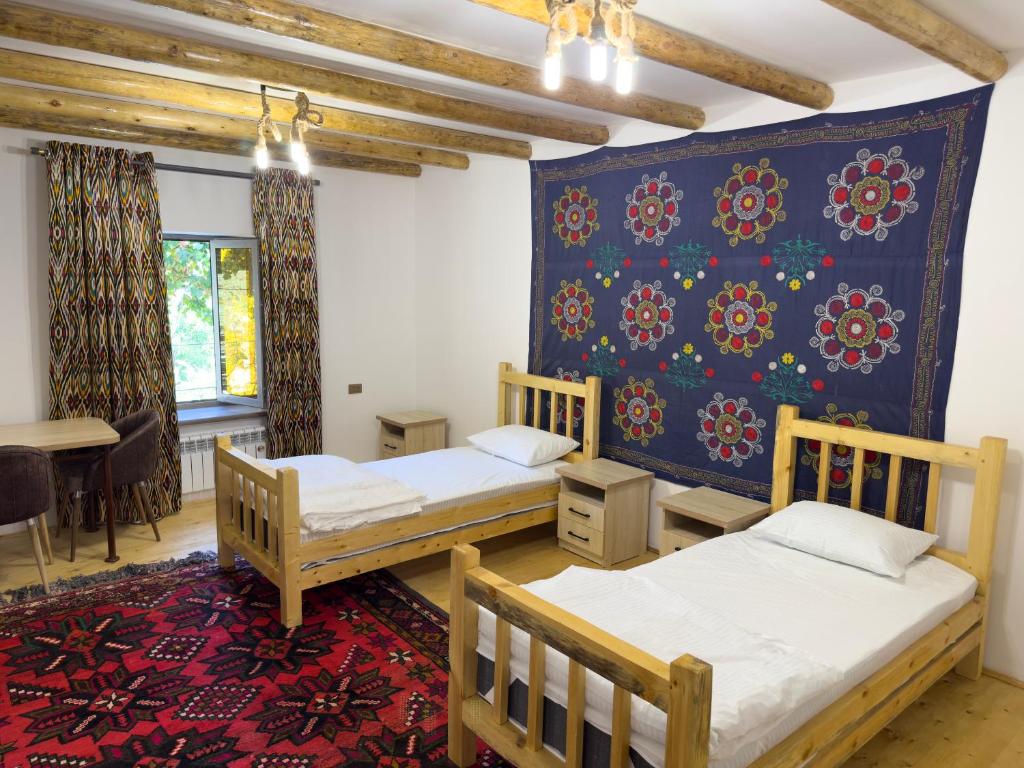 Un dormitorio con dos camas y una pared azul. en Yulduz Homestay, en Sayyod