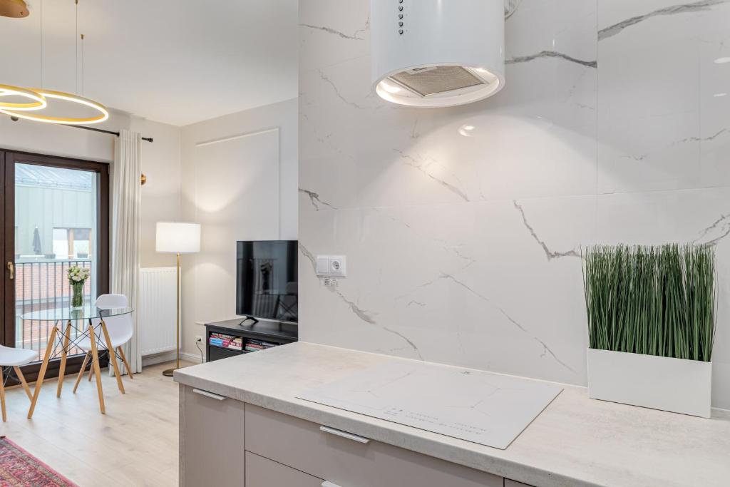 a kitchen with white marble countertops and a tv at Perfect Location - Modern Riverside Apartment in Warsaw